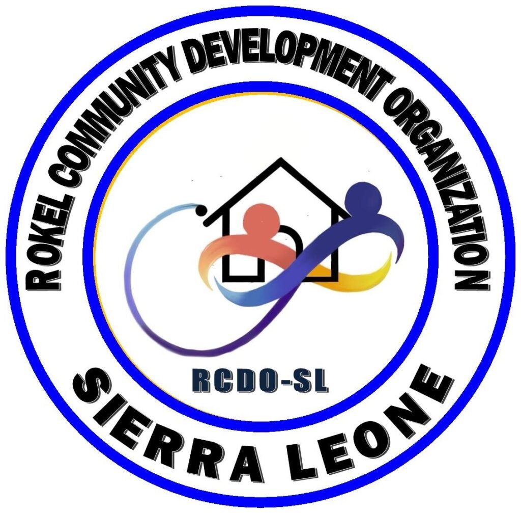 Circular seal for ROKEL Community Development Organization (RCDO-SL): stylized house with two colorful abstract figures and a looping ribbon; outer ring reads 'ROKEL COMMUNITY DEVELOPMENT ORGANIZATION' and 'SIERRA LEONE'.
